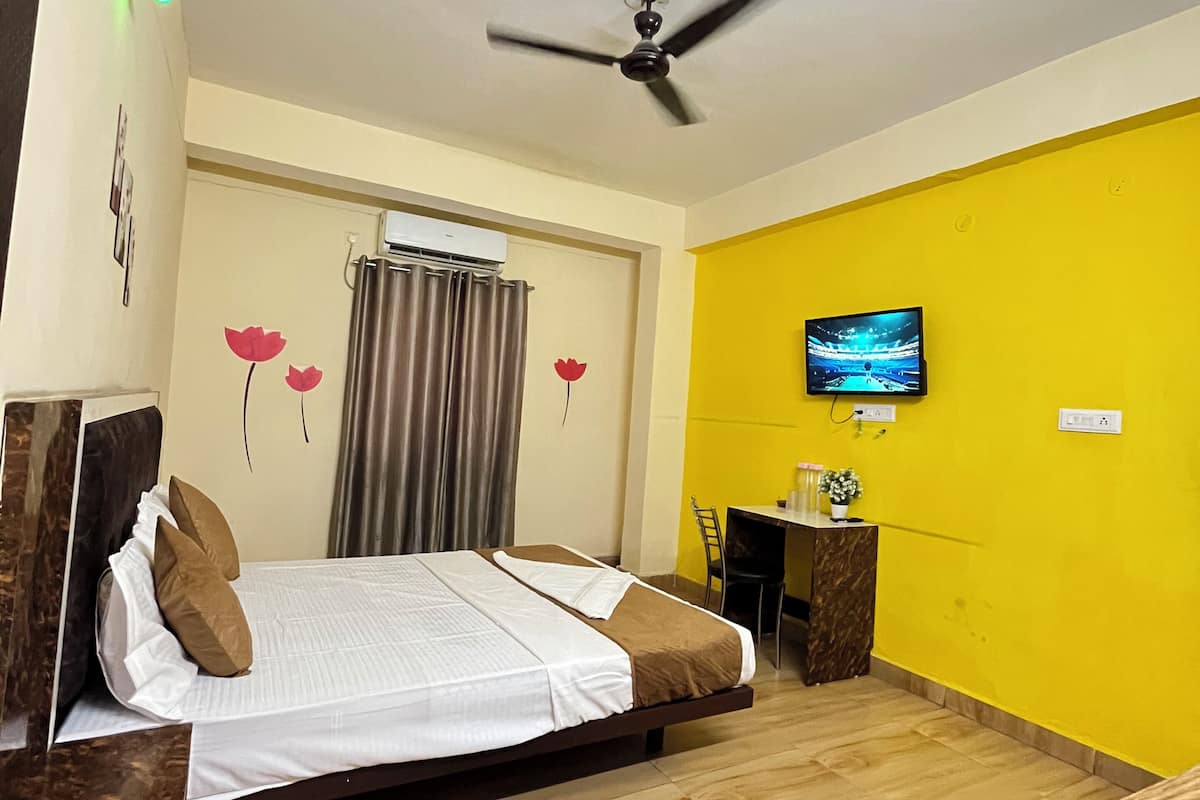 A hotel room with a bed, a desk, a television, and a ceiling fan.