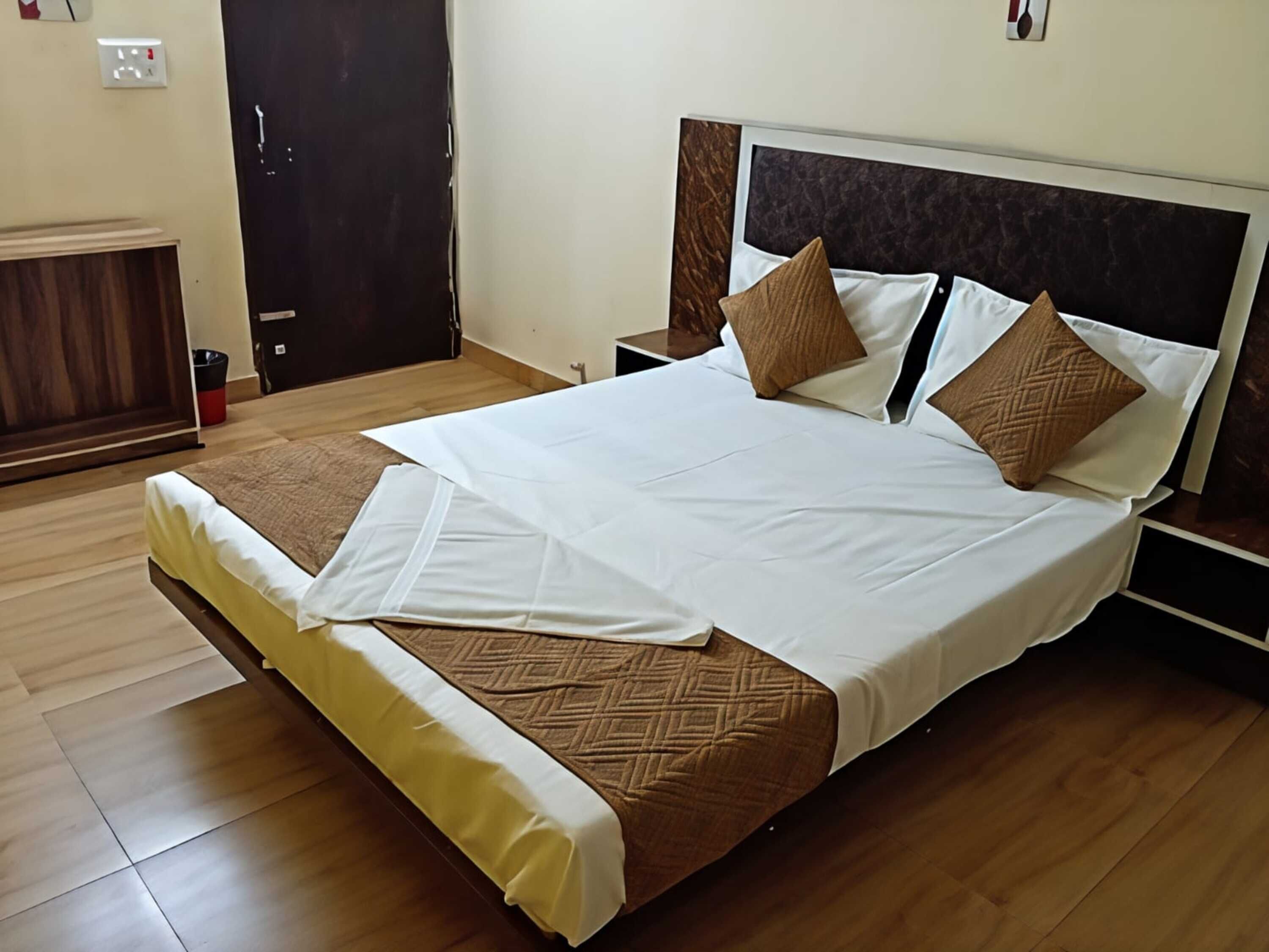 A neatly made bed with a brown and white bedspread, a wooden headboard, and two nightstands with a small table on one.