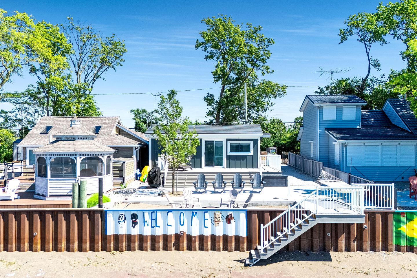 Une propriété située en bord de mer, dotée d’une terrasse couverte, d’un petit kiosque et d’une piscine délimitée par une clôture.