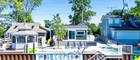 Une propriété située en bord de mer, dotée d’une terrasse couverte, d’un petit kiosque et d’une piscine délimitée par une clôture.