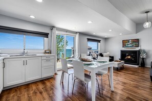 A modern kitchen with a dining area, a fireplace, and a view of the sea. - Gorgeous Cottage with Fire Pit and Nice Beach Vistas in Leamington, Ontario (Leamington)