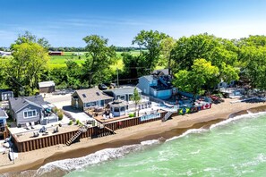 A coastal property with multiple buildings, a beach, and a view of the ocean. - Gorgeous Cottage with Fire Pit and Nice Beach Vistas in Leamington, Ontario (Leamington)
