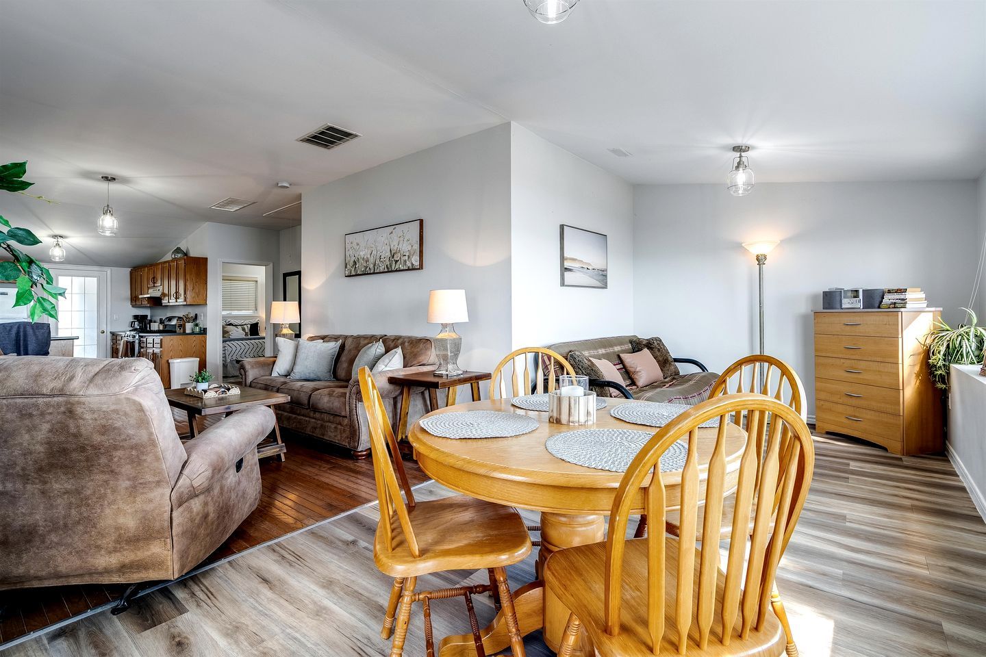 Una sala de estar moderna con una mesa de comedor, sofás y una cocina al fondo.