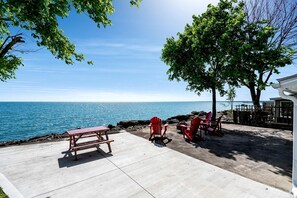 En terrasse med et træbord og stole, der kigger ud over vandet.