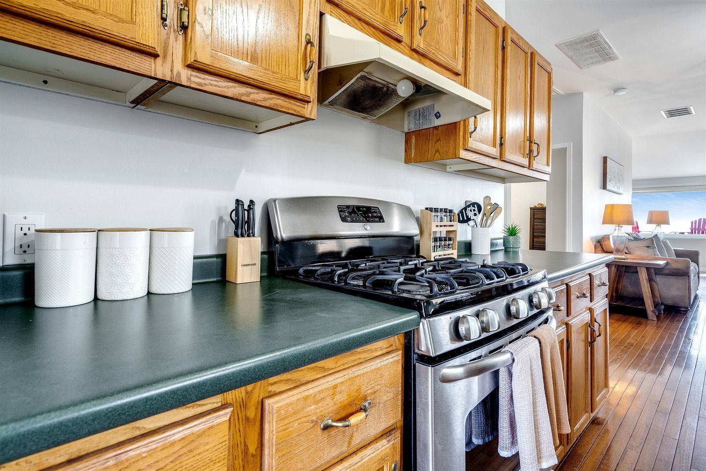 A kitchen with wooden cabinets, a stainless steel stove, and a green countertop.