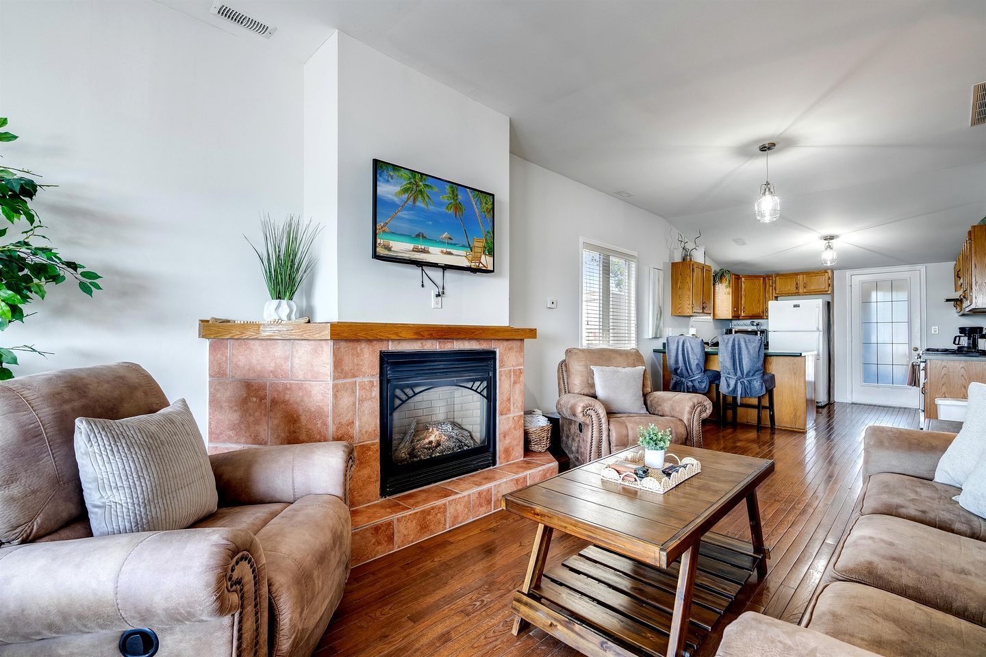 A living room with a fireplace, leather sofas, a coffee table, and a kitchen in the background.