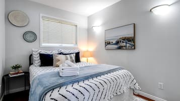 Ein ordentlich eingerichtetes Schlafzimmer mit einem Bett, Nachttischen, einer Lampe und Wandbildern.