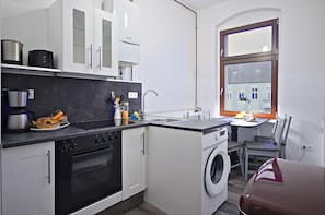 Eine kompakte Küche mit Herd, Backofen, Mikrowelle und Waschmaschine.