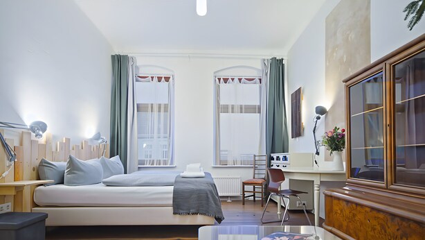 Una habitación moderna con cama, escritorio, silla y ventanas amplias.