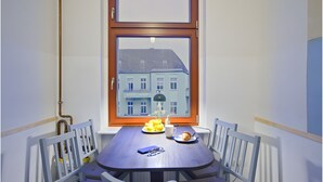 Comedor con una mesa, sillas y vista a un edificio desde la ventana.