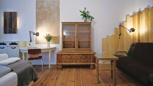 Una habitación con cama, escritorio, armario, silla, sofá y una escalera de madera.