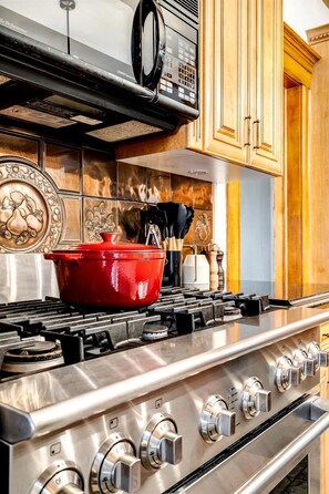 A kitchen with a stainless steel stove, a red pot, and wooden cabinets. - Luxurious Vacation Rental near Lake Erie for an Amazing Family Retreat in Leamington, Ontario (Leamington)