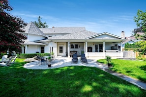 A two-story house with a covered patio, a lawn, and a small garden. - Luxurious Vacation Rental near Lake Erie for an Amazing Family Retreat in Leamington, Ontario (Leamington)