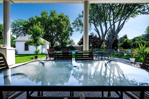 A glass-enclosed outdoor pool with a patio area, surrounded by trees and a white house. - Luxurious Vacation Rental near Lake Erie for an Amazing Family Retreat in Leamington, Ontario (Leamington)