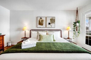 A neatly arranged bedroom with a bed, two bedside tables, a hanging plant, and two framed pictures on the wall. - Luxurious Vacation Rental near Lake Erie for an Amazing Family Retreat in Leamington, Ontario (Leamington)