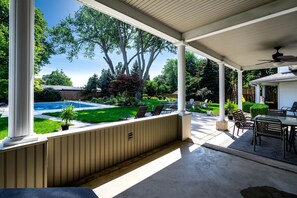 A covered patio with a pool, outdoor furniture, and a view of the backyard. - Luxurious Vacation Rental near Lake Erie for an Amazing Family Retreat in Leamington, Ontario (Leamington)