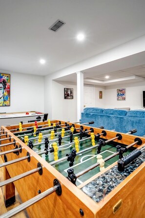 A room with a foosball table, a sofa, and a television. - Luxurious Vacation Rental near Lake Erie for an Amazing Family Retreat in Leamington, Ontario (Leamington)