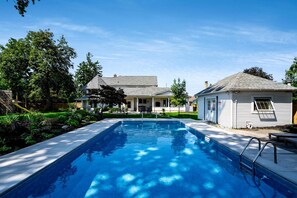 A residential swimming pool with a clear blue water surface, surrounded by a well-maintained lawn and trees. - Luxurious Vacation Rental near Lake Erie for an Amazing Family Retreat in Leamington, Ontario (Leamington)
