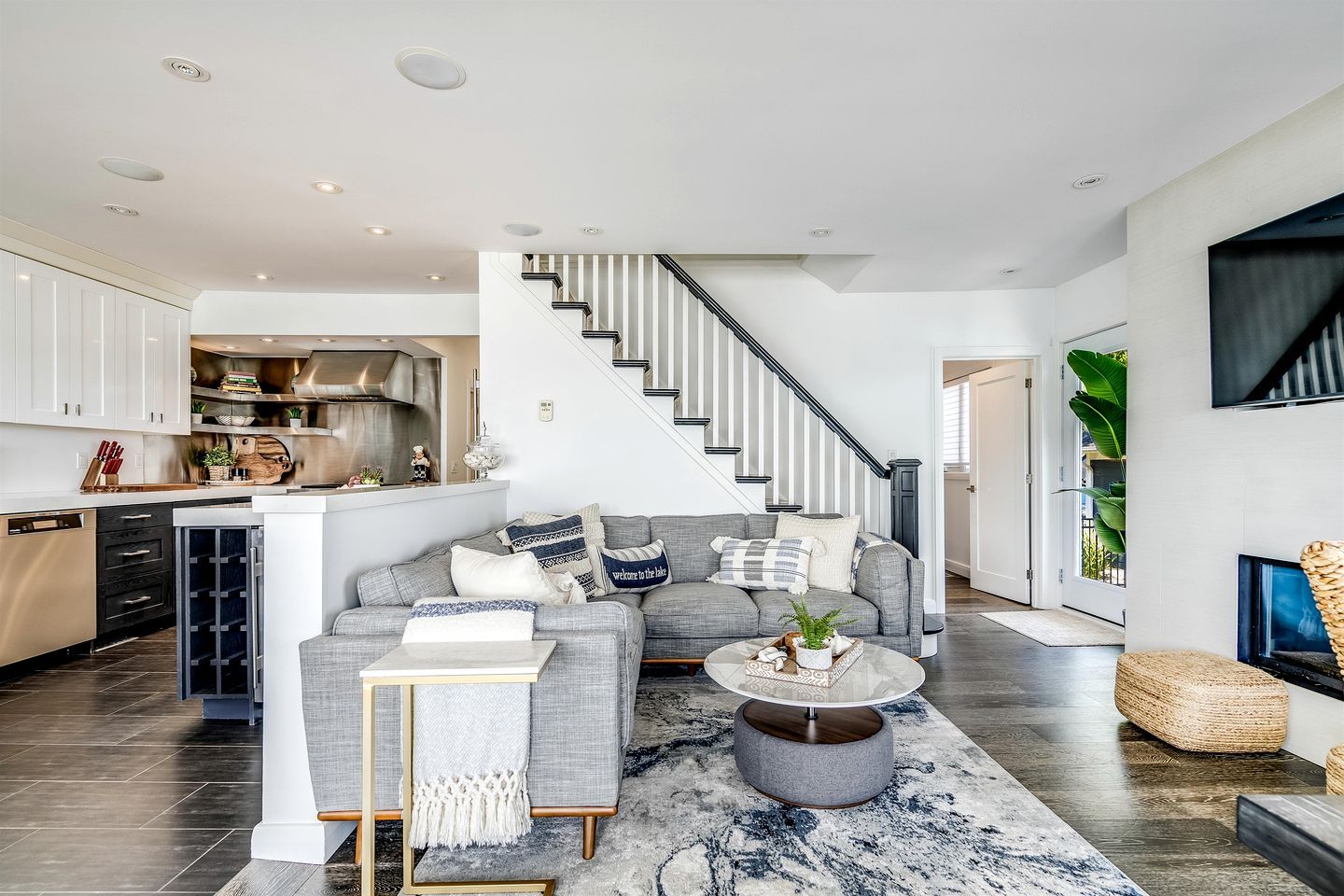 Un vaste espace de vie comprenant un canapé gris, une table basse et un escalier menant à l’étage supérieur.
