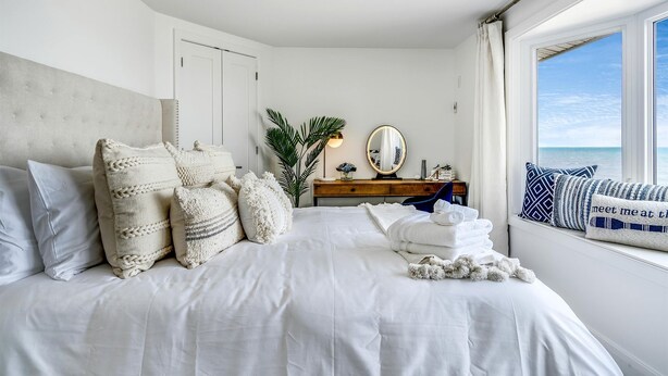 Un dormitorio con una cama grande, un aparador, un espejo y una ventana con vistas.