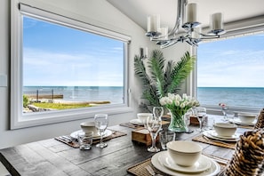 A dining area with a view of the ocean, a chandelier, and a table set for a meal. - Beautiful Cottage with Swimming Pool in Kingsville, Ontario (Kingsville)