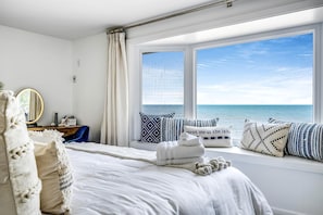 A bedroom with a large window, a bed with white linens, a bedside table with a mirror, and decorative pillows. - Beautiful Cottage with Swimming Pool in Kingsville, Ontario (Kingsville)