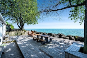 Een houten terras met een picknicktafel en stoelen, met uitzicht op een waterpartij.