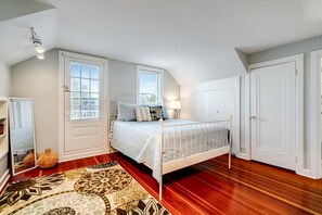 A bedroom with a bed, a mirror, a window, a door, and a patterned rug. - Serene Cottage with Private Deck by Lake Erie for a Peaceful Getaway in Kingsville, Ontario (Leamington)