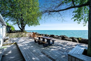 Eine Holzterrasse mit Picknicktisch und Stühlen mit Blick auf ein Gewässer.