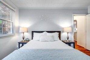 Ein Schlafzimmer mit einem großen Bett, zwei Nachttischen mit Lampen, einem hölzernen Kopfteil und einer Wanddekoration.
