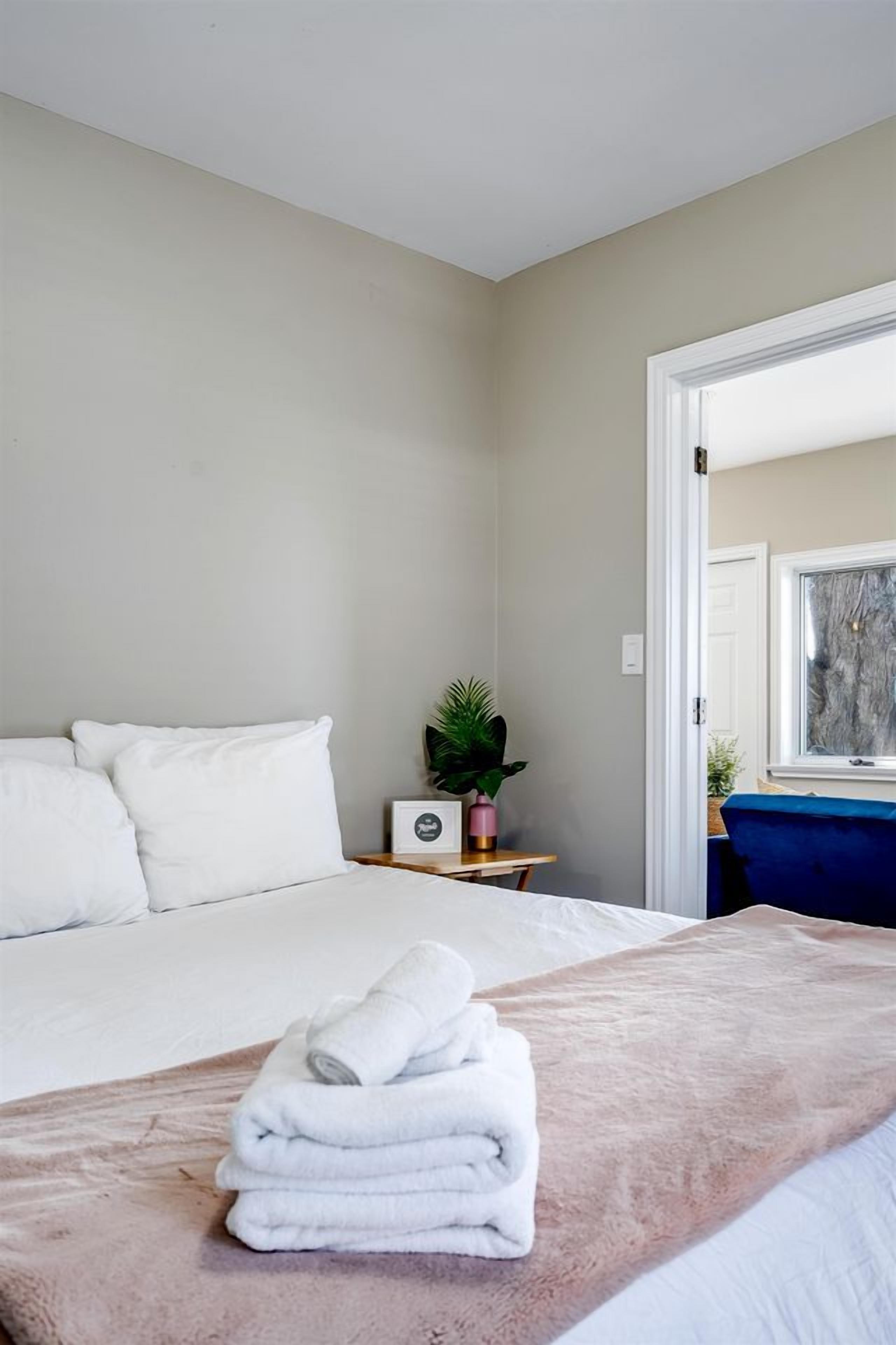 Un dormitorio con una cama, una mesita de noche con una planta y una ventana.