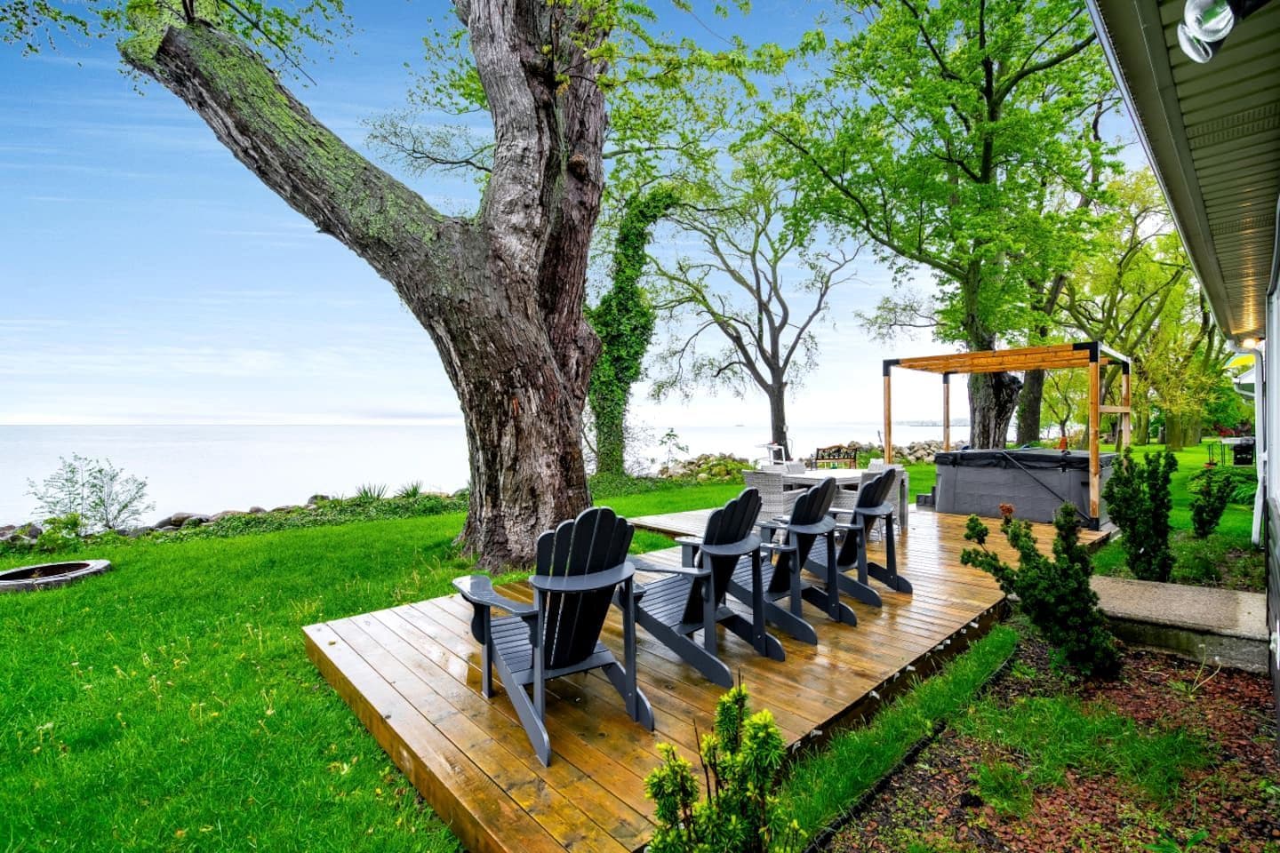 A deck with outdoor furniture, a pergola, and a view of the sea.