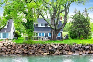 Ein Haus mit einer Terrasse, einer Steinsäule und einem großen Baum.