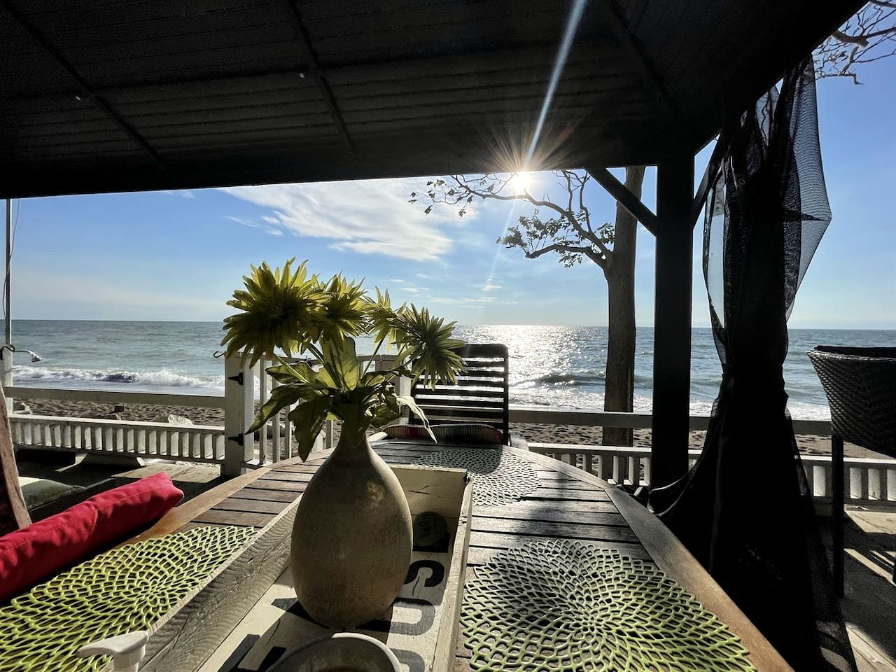 Eine Strandlounge mit Blick auf das Meer, einem Holztisch und einem Blumentopf.