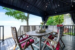 Un espace extérieur abrité, avec une table et des chaises, donnant sur une étendue d’eau.