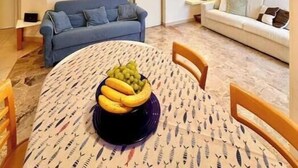 Ein modernes Wohnzimmer mit einem runden Esstisch, einem blauen Sofa und einem weißen Sofa.