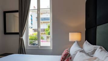 A hotel room with a bed, a window with curtains, a bedside lamp, and a view of the outside.
