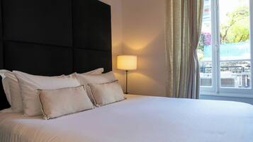 A hotel room with a large bed, a bedside lamp, and a view of the outdoors.