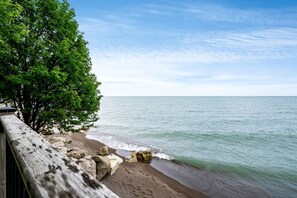 A beach with a wooden walkway, a rocky shoreline, and a clear sky. - Amazing Beachfront Cottage with Barbecue in Leamington, Ontario (Leamington)
