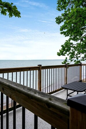 A wooden deck with a metal railing overlooking a body of water. - Amazing Beachfront Cottage with Barbecue in Leamington, Ontario (Leamington)