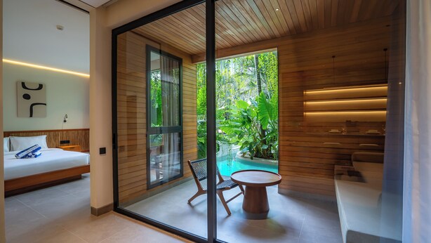 Une chambre moderne avec un lit, une porte vitrée donnant sur une piscine et une petite table avec des chaises.