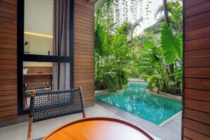 A modern pool area with a wooden bench, surrounded by lush greenery and a clear pool. - Novo Ubud by Betterplace (Ubud)