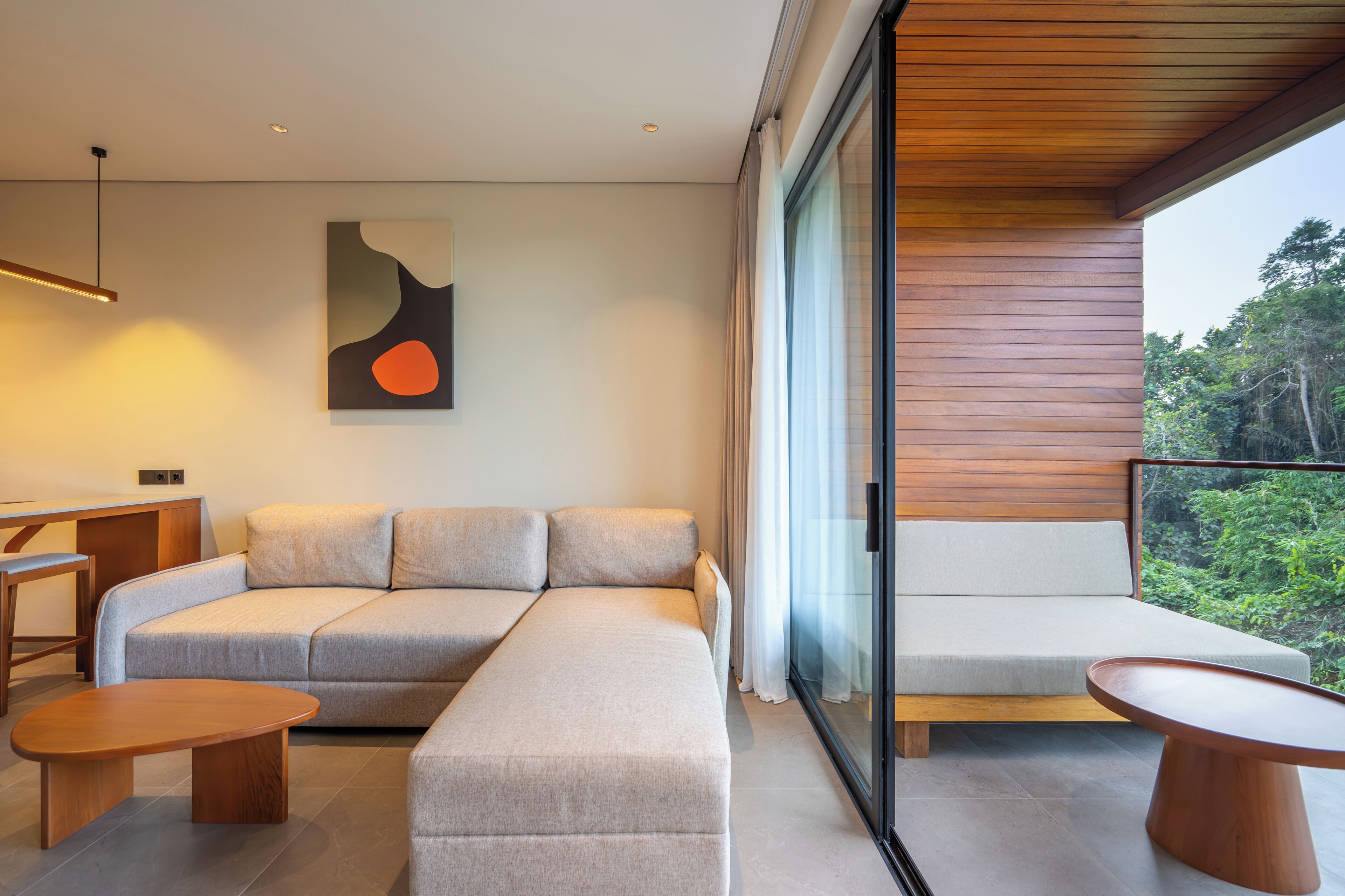 A modern living room with a sofa, two wooden side tables, and a painting on the wall.