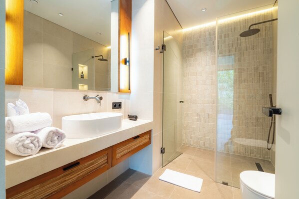 A modern bathroom with a large mirror, white sink, and a glass-enclosed shower area. - Novo Ubud by Betterplace (Ubud)
