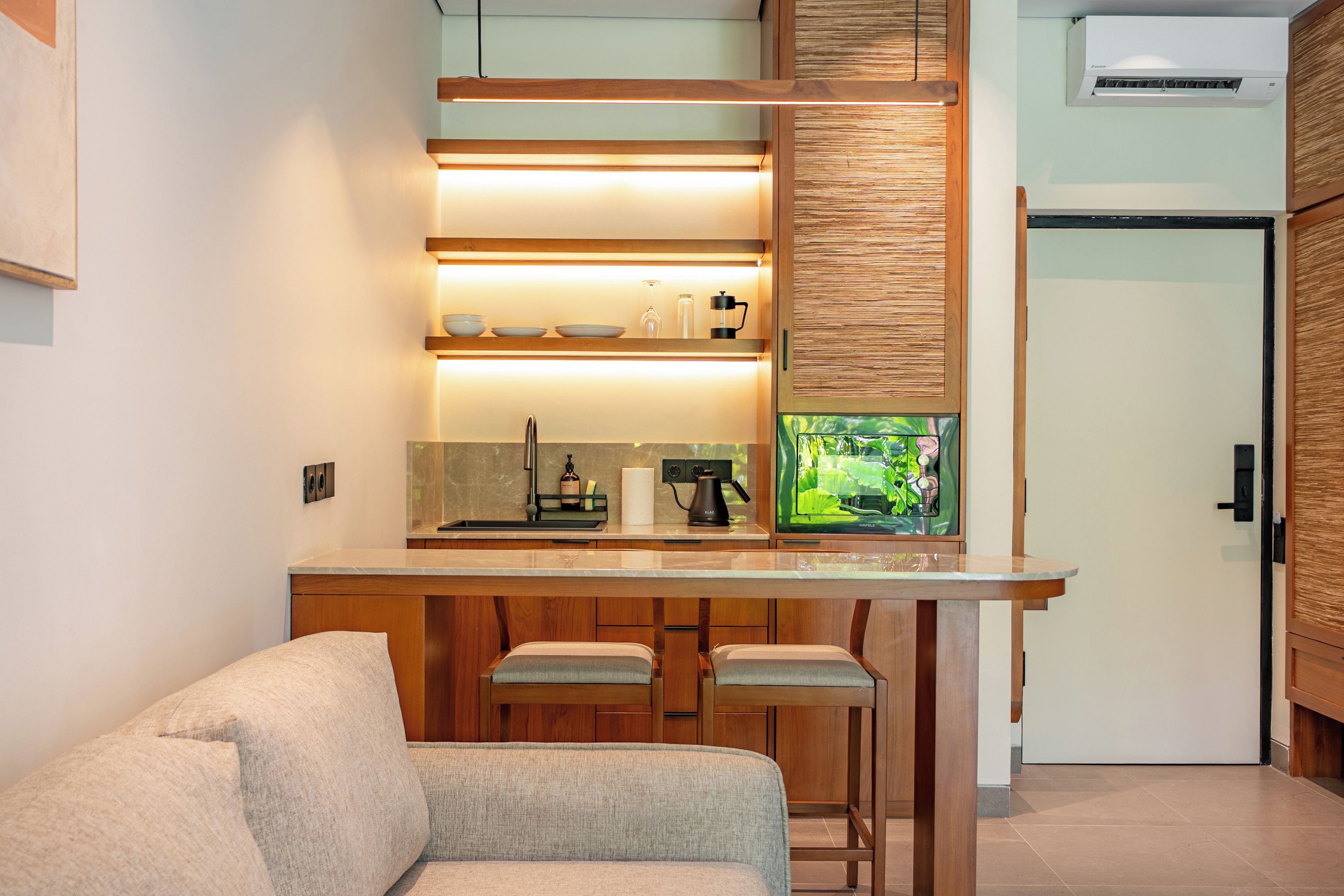 A modern kitchen with a wooden countertop, bar stools, and a built-in coffee machine.