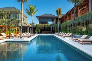 A swimming pool with lounge chairs and palm trees. - Novo Ubud by Betterplace (Ubud)