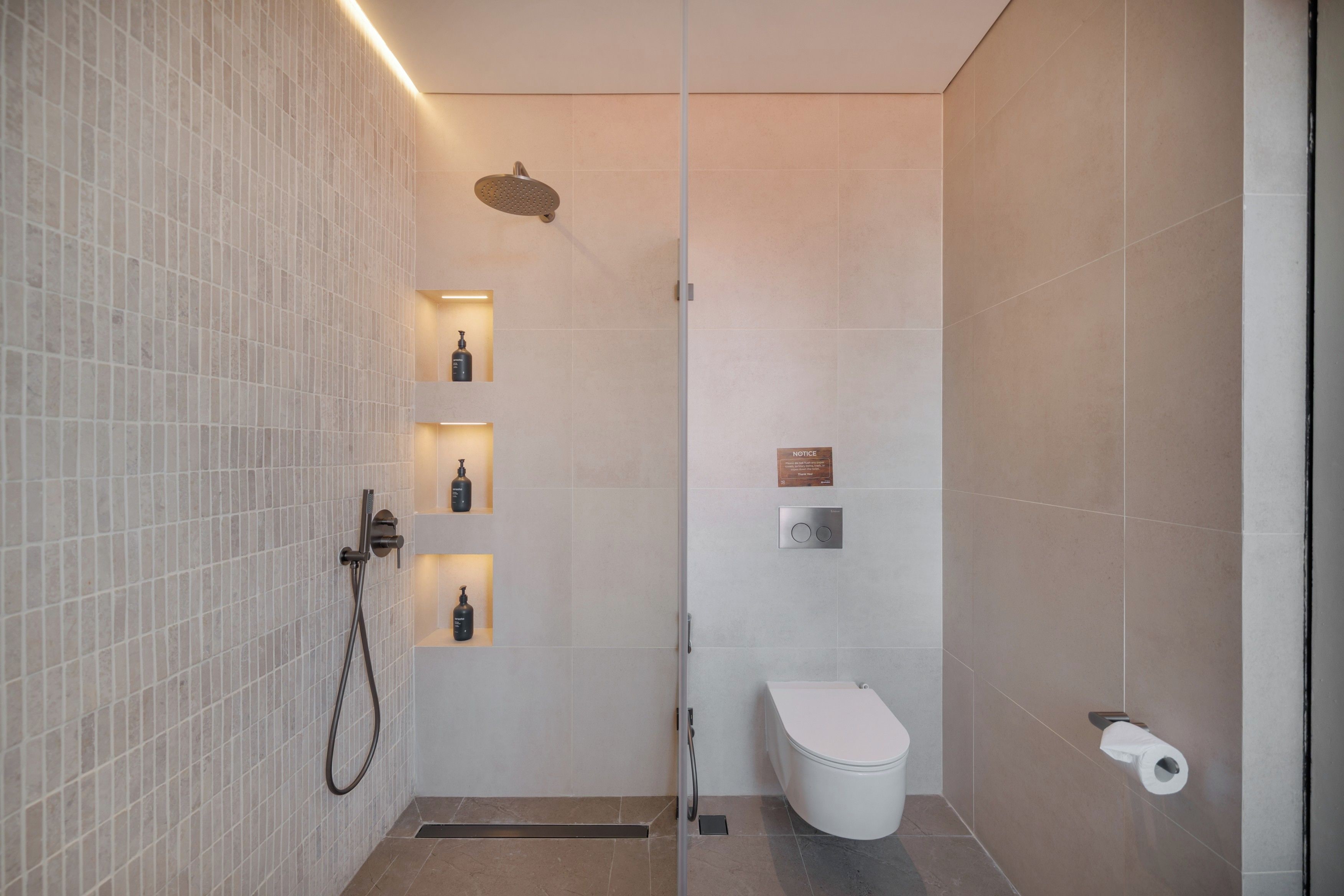 A modern bathroom with a glass partition, a showerhead, and a toilet.