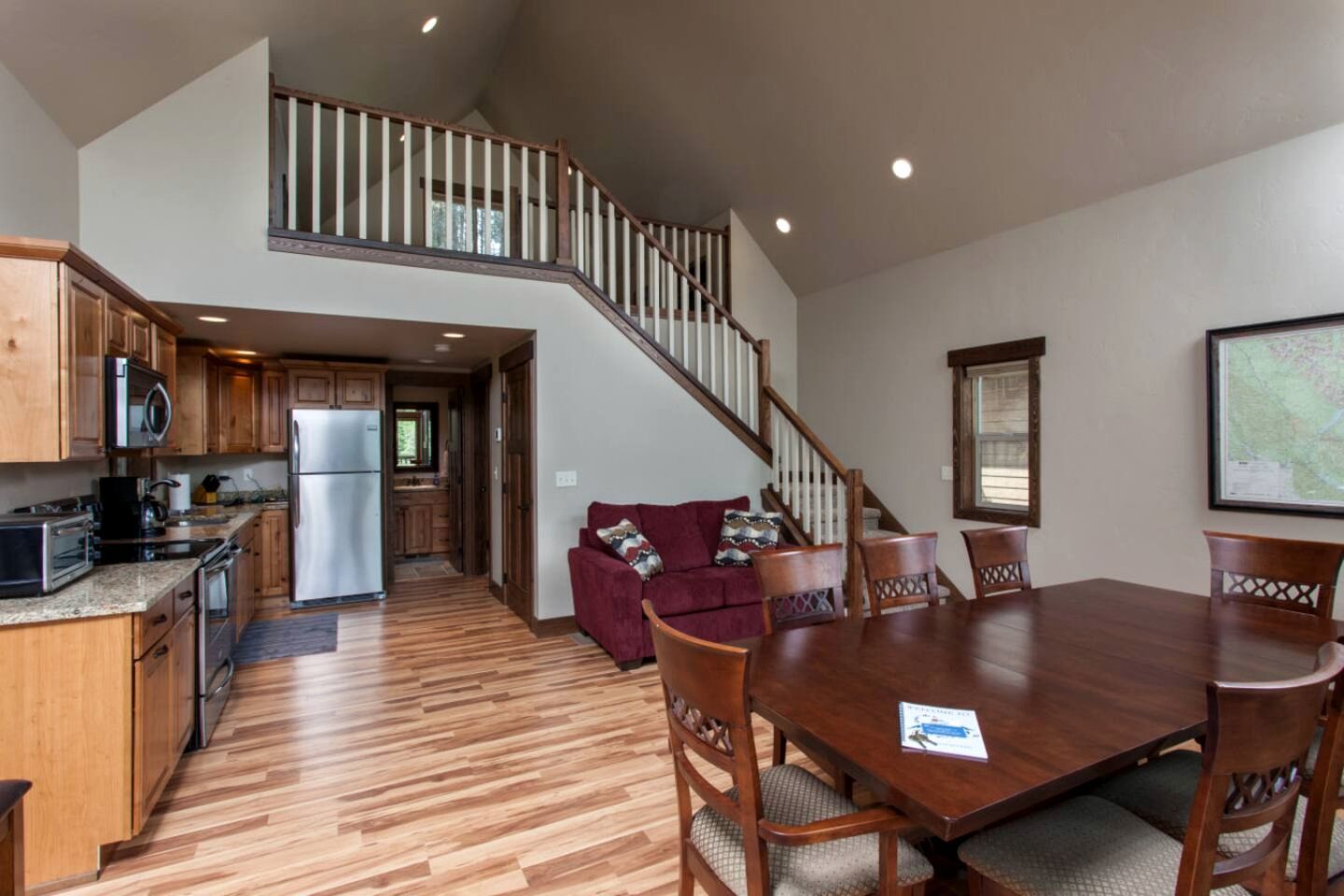 A spacious kitchen with modern appliances, a dining area with wooden furniture, and a staircase leading to an upper level.