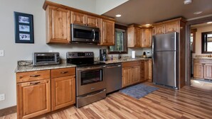 A kitchen with wooden cabinets, stainless steel appliances, and a granite countertop. - Family-Friendly Cabin Rental with Mountain Vistas near West Glacier, Montana (West Glacier)