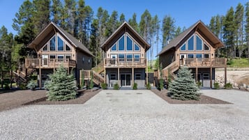 A three-story lodge with a central entrance, wooden balconies, and a gravel driveway.